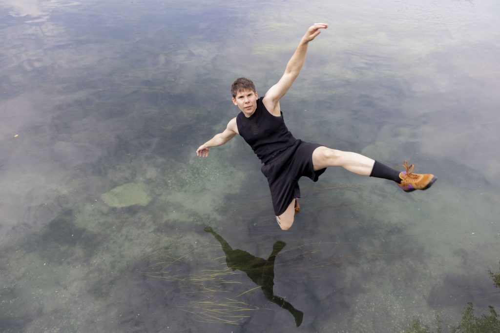A masc person falling into the river rhine, staring intently into the camera.